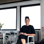 Confident young professional woman enjoying a coffee break in a modern office environment.